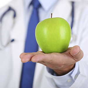 Photo: Male medicine doctor hands holding green fresh ripe apple. 