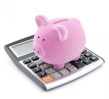 Pink piggy bank standing on a calculator