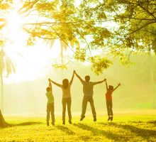 A family of four jumping in the air raising their hands together