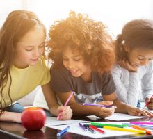 3 children smiling and coloring together